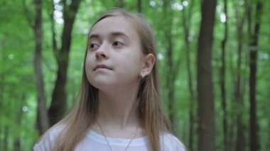 Portrait of a pretty girl walking alone in the forest. A teenager with long hair walks in the forest during the day. High quality 4k footage