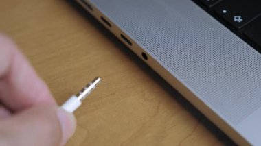 Adamın biri kulaklığa kulaklık takıyor. Adamın kulaklık konnektörüyle dizüstü bilgisayara kablo yerleştirdiği yakın plan. Kulaklıkları kabloyla bilgisayara bağlıyorum. Yüksek kalite 4k görüntü