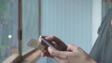 Bir kadın tarar, telefon kullanarak kart numarasını okur. Kız telefonu kullanarak alışveriş yapıyor. İnternetten satın almak. Kadınların elleri kapalı olsun. Yüksek kalite 4k görüntü