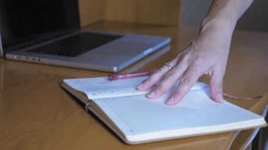 The girl opens a notebook, takes a ballpoint pen and makes a note in a notebook. A woman writes plans in a notebook. High quality 4k footage