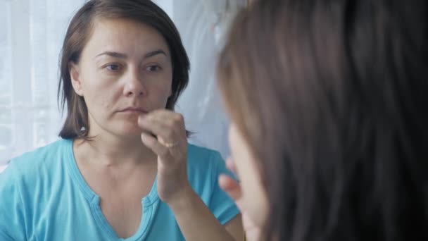 Caucasian Woman Stands Front Mirror Runs Her Hand Her Face — Vídeo de Stock