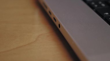 A man puts headphones into the headphone jack of a laptop. Close-up of man inserting wire with headphone connector into laptop. Connecting headphones to laptop via wire. High quality 4k footage