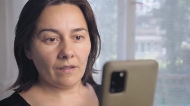 Caucasian woman is surprised by a phone call. A girl with short dark hair reacts emotionally to the caller on the phone. High quality 4k footage