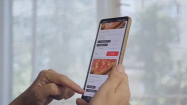 The girl orders pizza at home on the Internet. A woman is standing in her kitchen ordering food online. 25.07.2022 Ukraine Vinnitza. High quality 4k footage