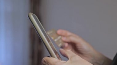 Kız telefonu kullanarak alışveriş yapıyor. İnternetten satın almak. Kadınların elleri kapalı olsun. Kız evde olduğu için telefonla bir şeyler alıyor. Yüksek kalite 4k görüntü