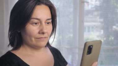 Caucasian woman is surprised by a phone call. A girl with short dark hair reacts emotionally to the caller on the phone. High quality 4k footage