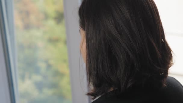 Girl Short Dark Hair Stands Window Room Admires View Lonely — Stockvideo