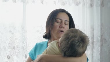 Mom is holding her little baby in her arms. Mom sings a lullaby while rocking a small child. High quality 4k footage