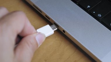 A man inserts a Type C cable into a laptop connector. Data transfer from phone, phone charging. High quality 4k footage