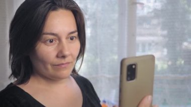 Caucasian woman is surprised by a phone call. A girl with short dark hair reacts emotionally to the caller on the phone. High quality 4k footage