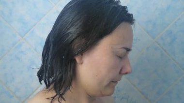 Caucasian girl takes a shower in the morning. A woman with short dark hair bathes in the shower. High quality 4k footage