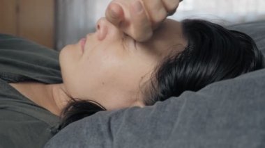 A tired young woman lies on a bed during the day, and runs her hand over her head. The concept of a frustrated state, depression, hopelessness. High quality 4k footage