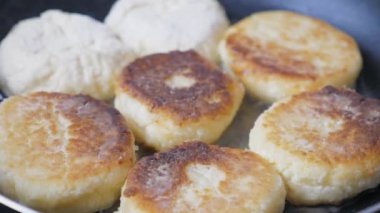 Many cheesecakes are fried in a frying pan on an electric stove. Breakfast preparation. High quality 4k footage