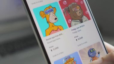 The girl looks through the nft auction in the browser on the smartphone. A woman makes a purchase of nft pictures. Online NFT marketplace selling Non-fungible token on a smartphone. Artistic NFT Non