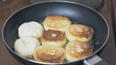 Many cheesecakes are fried in a frying pan on an electric stove. Breakfast preparation. High quality 4k footage