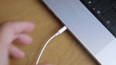 Birisi kulaklığı bir dizüstü bilgisayarın kulaklığına takıyor. Kulaklık kablosunu dizüstü bilgisayara çeken birinin yakın çekimi. Kulaklığı laptoptan çıkarıyorum. Yüksek kalite 4k görüntü