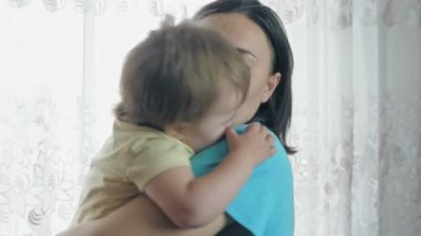 Annem kucağında küçük bir çocukla dans ediyor. Kız odada dikilirken bebeği sallar. Yüksek kalite 4k görüntü