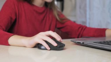 Kırmızı kazaklı genç bir kız mutfaktaki sandalyede otururken dizüstü bilgisayarda oyun oynuyor. Çocuk ev ödevi yapmak yerine dizüstü bilgisayarda oynuyor. Yüksek kalite 4k görüntü