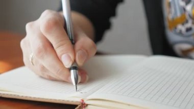 Deftere kalemle yazan bir kadın, yakın plan. Kız bugün için bir yapılacaklar listesi hazırlıyor. Kafkasyalı kadın bugün gol yazıyor. Yüksek kalite 4k görüntü