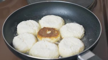 Many cheesecakes are fried in a frying pan on an electric stove. Breakfast preparation. High quality 4k footage