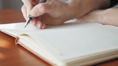 Deftere kalemle yazan bir kadın, yakın plan. Kız bugün için bir yapılacaklar listesi hazırlıyor. Kafkasyalı kadın bugün gol yazıyor. Yüksek kalite 4k görüntü