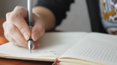 Deftere kalemle yazan bir kadın, yakın plan. Kız bugün için bir yapılacaklar listesi hazırlıyor. Kafkasyalı kadın bugün gol yazıyor. Yüksek kalite 4k görüntü
