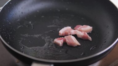 Çiğ pastırma dilimleri sıcak bir tavaya dökülür. Domuz eti akşam yemeği için pişirilir. Yüksek kalite 4k görüntü