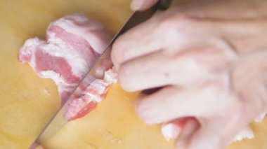Bir kadın elini keser ve domuz yağını parçalara ayırır. Tahtada keskin bir bıçakla çiğ et kesen biri. Yüksek kalite 4k görüntü