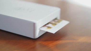 Mini yazıcı küçük bir çocuğun fotoğrafını basıyor. Akıllı telefonlar için kablosuz mini yazıcı. Evde taşınabilir bir yazıcıyla fotoğraf basma işlemi. Fotoğraf albümü için küçük baskılar. Yüksek kalite 4k