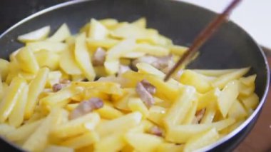 Etli patates pişirmek. Patates ve pastırma dilimleri sıcak tavada kızartılır. Bir insan yemek pişirirken patates karıştırır. Yüksek kalite 4k görüntü