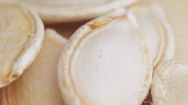 Masanın üzerinde bir balkabağı çekirdeği yığını yatıyor. Balkabağı tohumlarının makro videosu. Çiğ ayçiçeği çekirdekleri kapanıyor. Yüksek kalite 4k görüntü