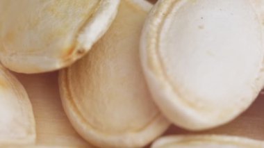 Masanın üzerinde bir balkabağı çekirdeği yığını yatıyor. Balkabağı tohumlarının makro videosu. Çiğ ayçiçeği çekirdekleri kapanıyor. Yüksek kalite 4k görüntü