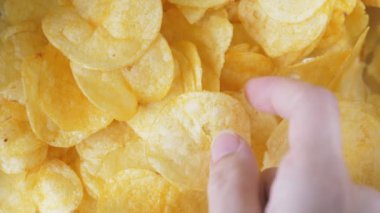 Bir kadının eli çıtır çıtır bir atıştırmalık alır. Masada bir yığın sağlıksız yiyecek yatıyor. İnsanlar çip alıyor, video yakından çekiliyor. Yüksek kalite 4k görüntü