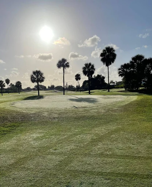 Golf sahası, yeşil ağaçlar ve güzel bir gökyüzü.