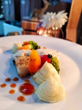 Patates püresi, domates, havuç ve brokoli ile servis edilen bal soslu somon balığı.