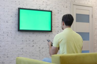 Kanepede oturan ve televizyon izleyen bir adam. Yeşil ekran konsepti