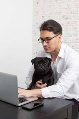 Ciddi bir iş adamı ve sevimli köpeği evde dizüstü bilgisayarla çalışıyor. Uzak çalışma ve arkadaşlık kavramları