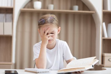 Evde kitap okuyan yorgun ve sıkılmış küçük bir kız. Avuç içi konsepti