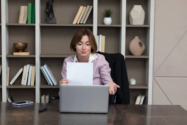 Serious business woman holding documents in her hand and working in modern office