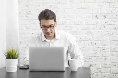 Evde dizüstü bilgisayarla çalışan genç bir iş adamı. Uzak çalışma konsepti