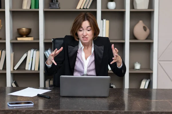 Angry female office worker demonstrating her irritation and dissatisfaction of work in the office