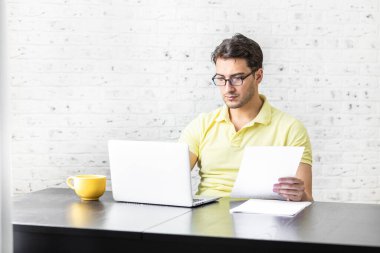Evde masada oturan ve çalışan ciddi bir serbest çalışan. Uzak çalışma konsepti
