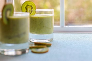 kiwi smoothie in a glass on blue table, blurred background 