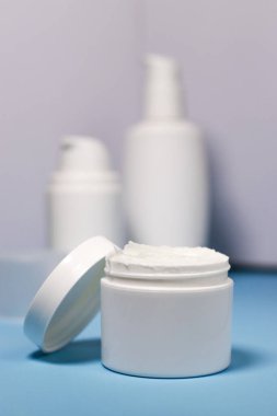 close up of mock up white jar with cream on a blue background