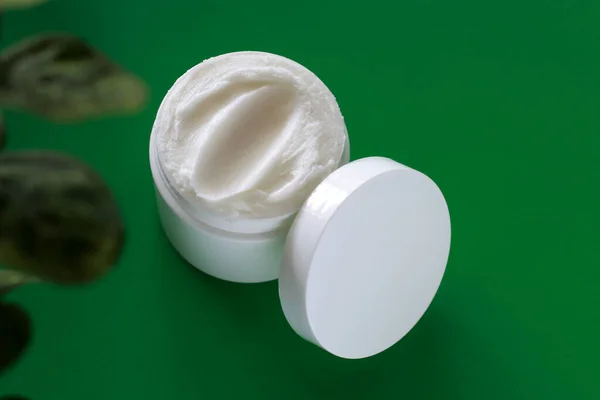 mock up of white jar of cream on a green background, with copy space