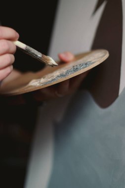 close up of hands of an artist with paint palette and brushes