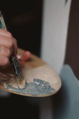 close up of hands of an artist with paint palette and brushes