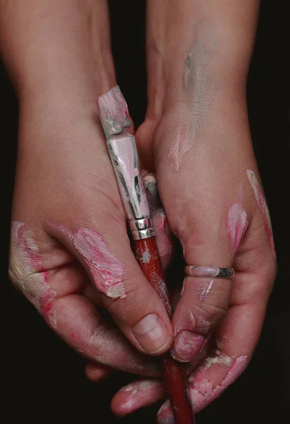 close up of hands of an artist with a brush in color