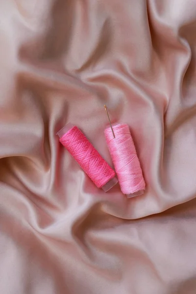 close up of a silk with pink sewing coil thread and needle