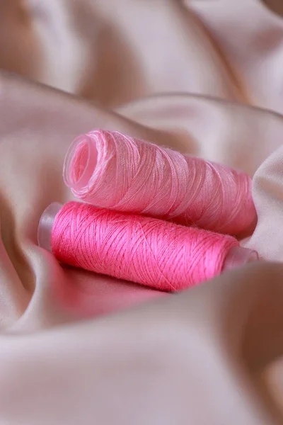 close up of a pink sewing coil thread on silk textile